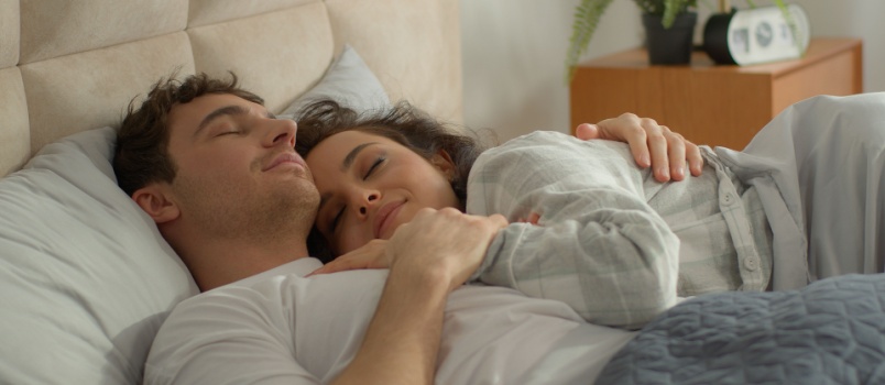 Young happy couple cuddling on bed