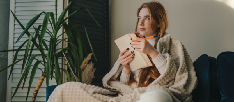 Woman sitting on couch writing book