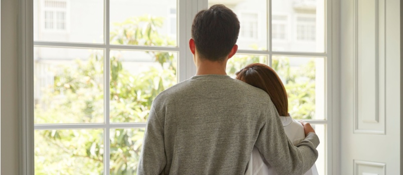 Young couple looking outside of the window