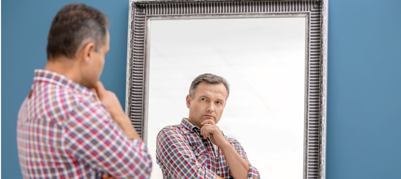 Thoughtful man looking in mirror