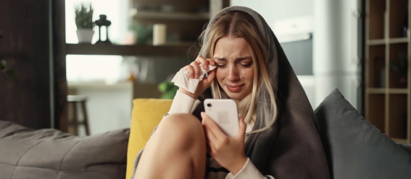 Woman crying while using smartphone
