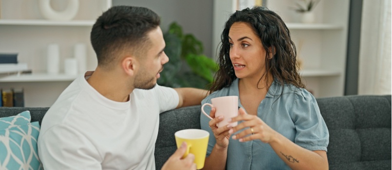 Couple sitting on couch having coffee