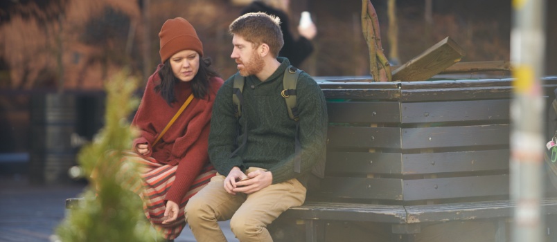 Young couple sitting in bench talking to each other