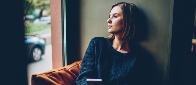 Sad woman looking outside of window
