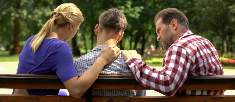 Mother and dad supporting sad teen