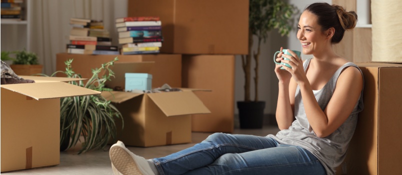 Young woman sitting on floor having coffee