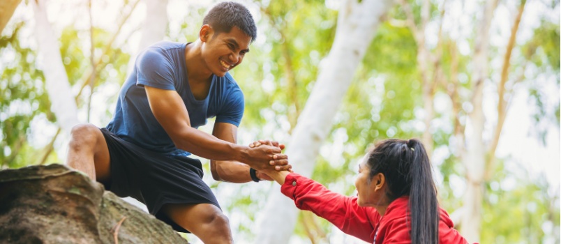 Hiking couple helping each other