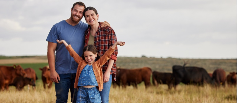 Happy family standing on cow farm
