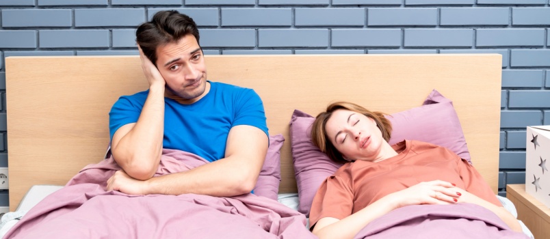 Young annoyed man sitting on bed