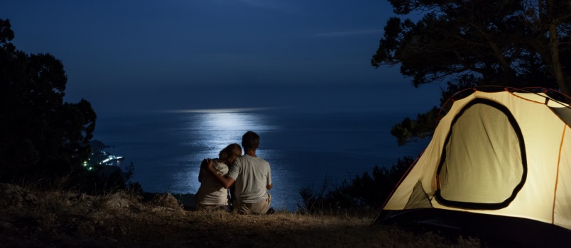 Couple sitting on beach watching moon