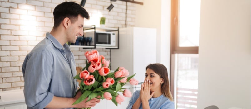 Man surprising woman with flowers