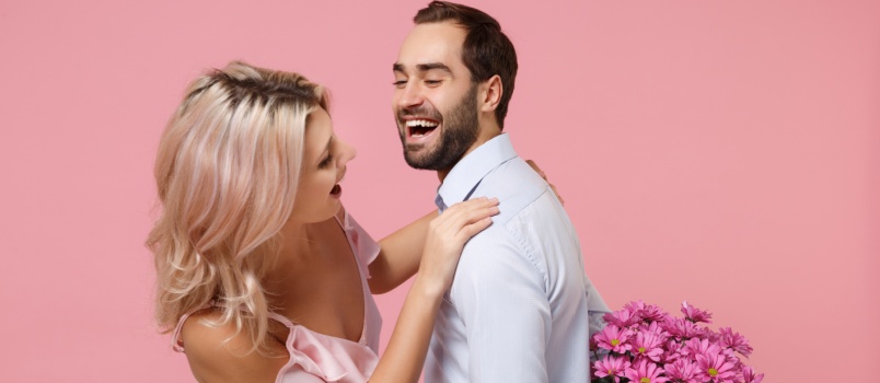 Man hiding flowers from woman