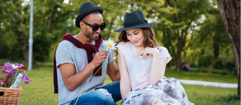 Smiling young man giving flowers to his girlfriend