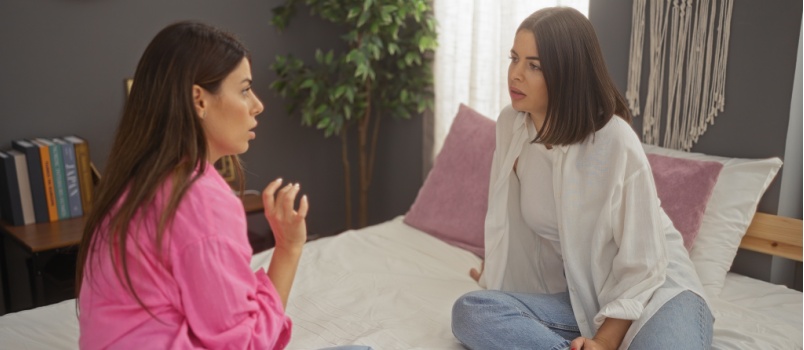 Female friend sitting at bed talking to each other