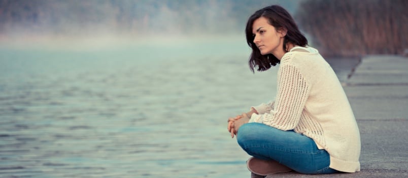 Woman sitting alone beside the river