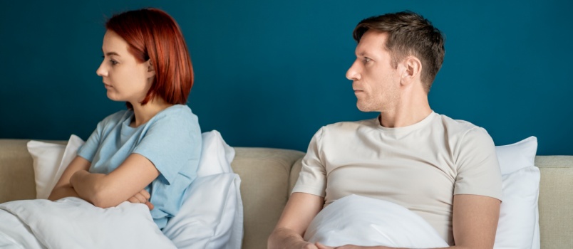 Couple sitting on bed not talking to each other