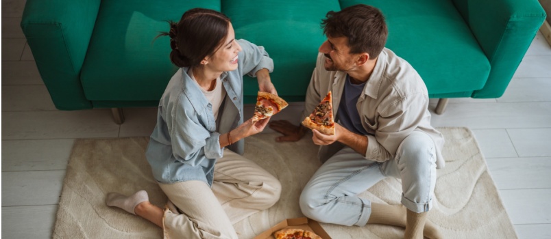 Couple sitting in living room having pizza