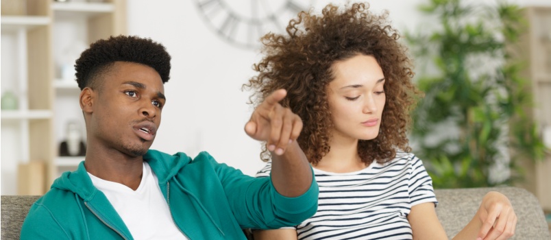Man playing video game while woman reading books