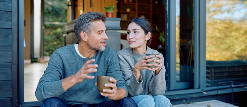 Couple sitting outside house having coffee
