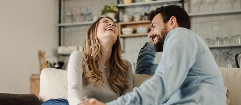 young loving couple sitting on couch talking to each other