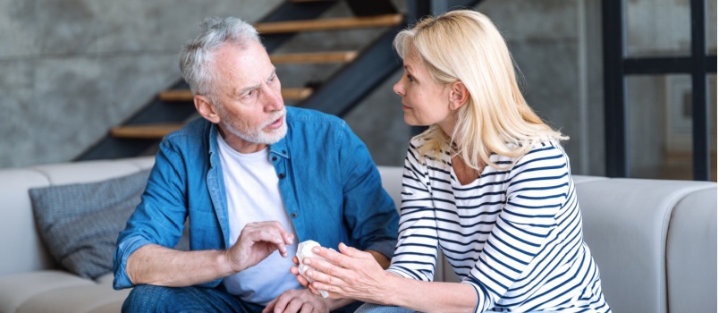 Mature couple sitting on couch talking to each other
