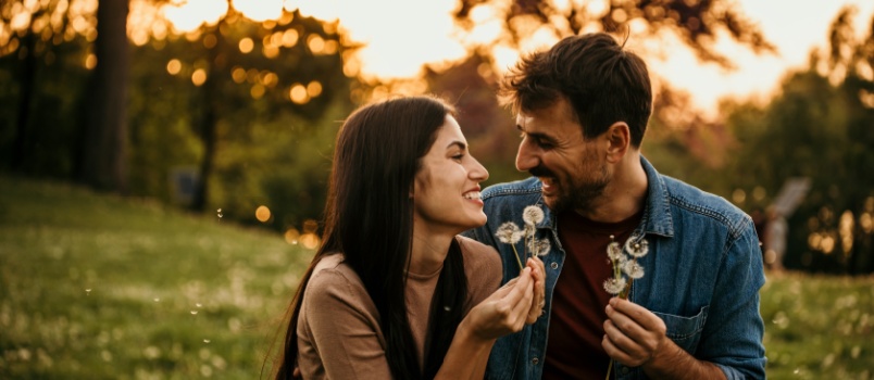 happy couple blowing dandelion sharing conversation