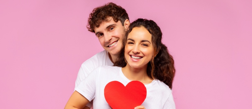Young couple embracing each other holding heart plank 