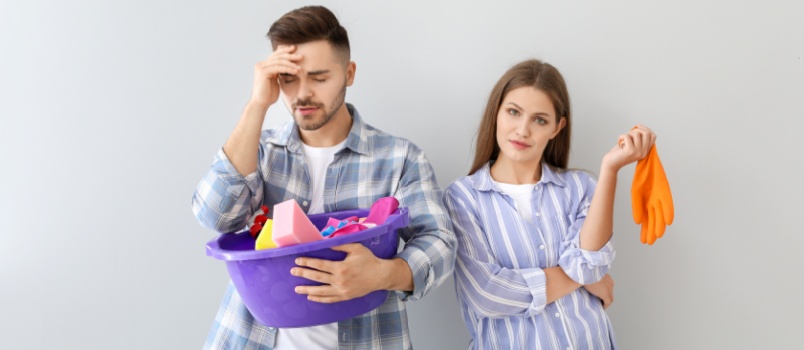Pareja estresada sosteniendo cosas de limpieza
