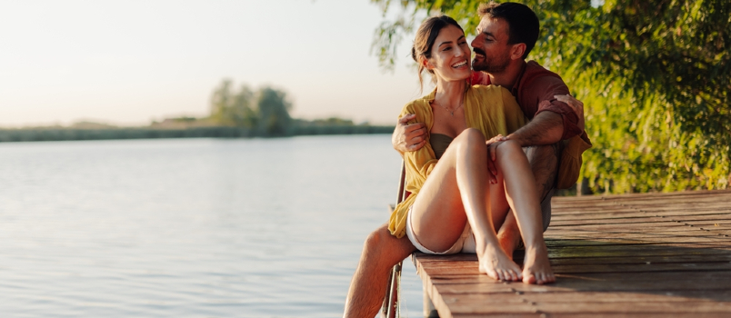 happy couple sitting on river side spending quality time