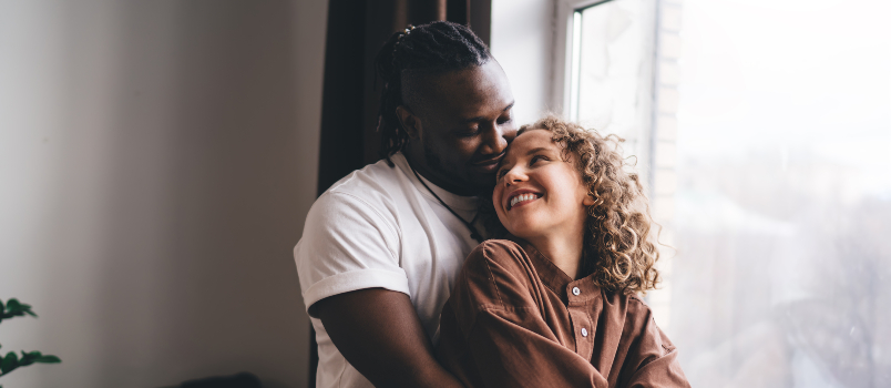 Loving Couple Embracing Near Window At Home