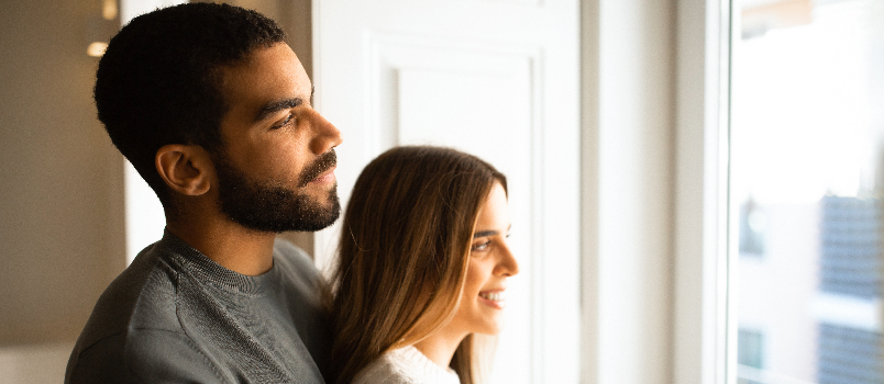 Affectionate Couple Embracing and Looking Out a Window