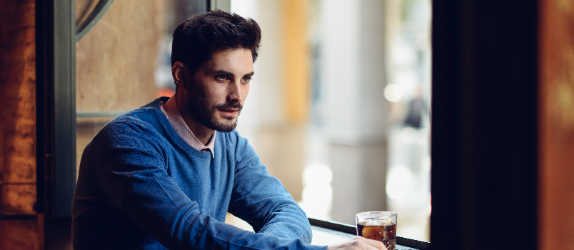Man Sitting at Window with Drink in Cafe