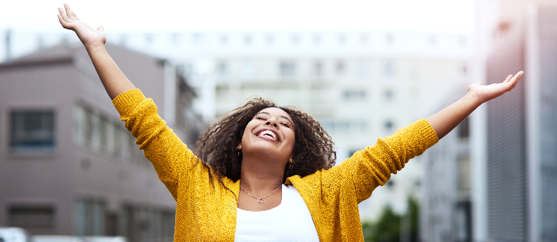 Woman Smiling Outdoors with Arms Raised in Joy