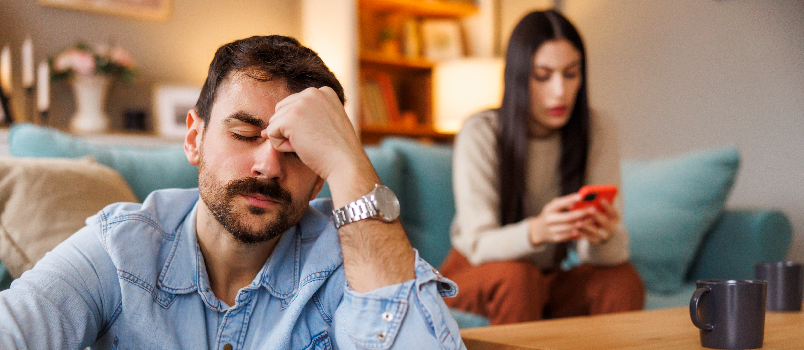 Homme stressé assis sur le sol pendant que son partenaire utilise un smartphone